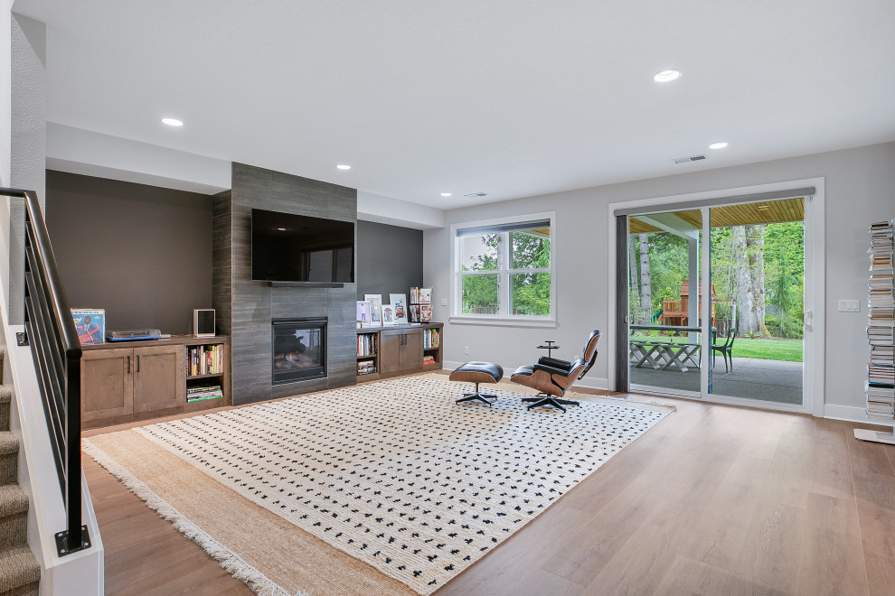 Large midcentury walk-out basement in Portland with a game room, grey walls, vinyl flooring, a standard fireplace, a tiled fireplace surround and beige floors.