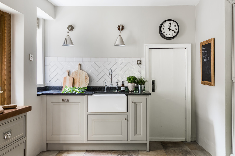 This is an example of a large traditional l-shaped eat-in kitchen in Other with a farmhouse sink, beaded inset cabinets, grey cabinets, wood benchtops, white splashback, ceramic splashback, panelled appliances, limestone floors, no island and multi-coloured floor.
