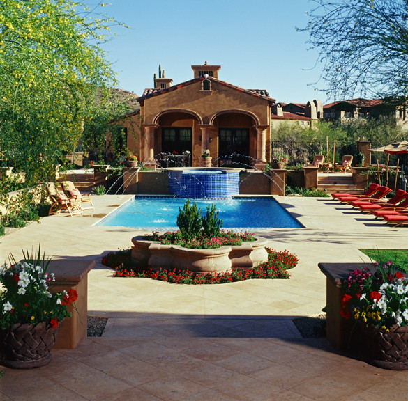 Photo of an expansive mediterranean backyard custom-shaped natural pool in Phoenix with a water feature and natural stone pavers.