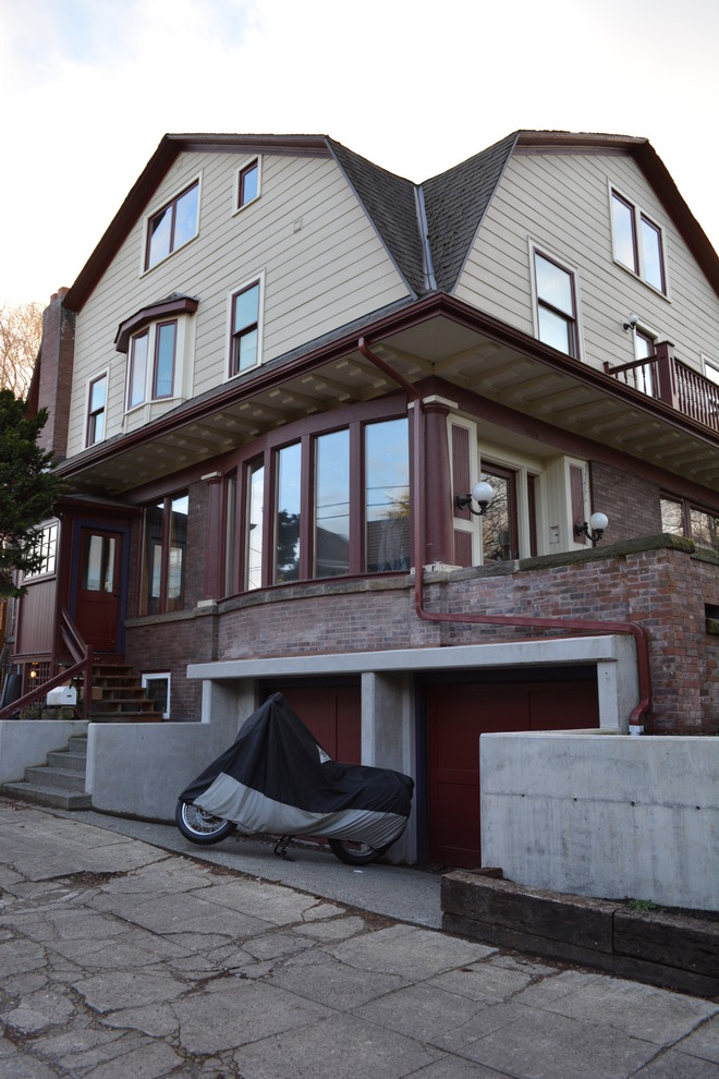 This is an example of a large arts and crafts three-storey brick red exterior in Seattle with a gambrel roof.