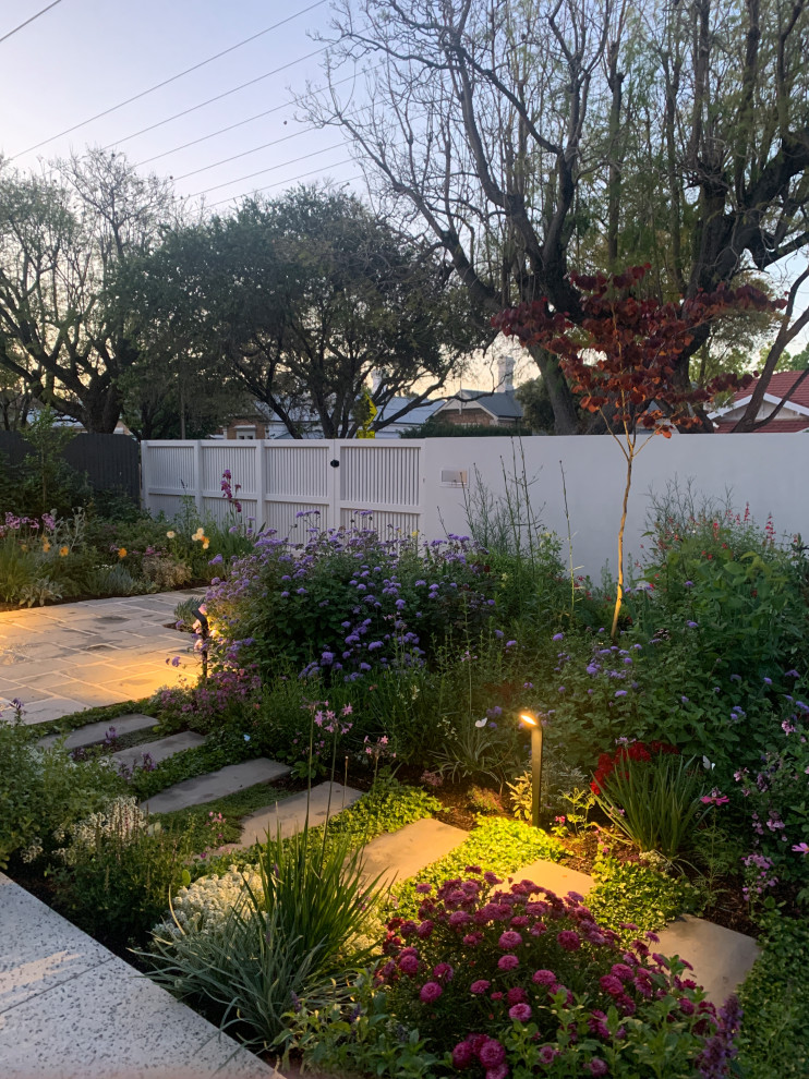 Photo of a mid-sized modern front yard full sun garden for spring in Adelaide with a garden path, natural stone pavers and a wood fence.