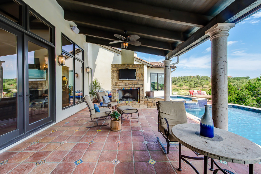 Large backyard patio in Austin with an outdoor kitchen, tile and a roof extension.