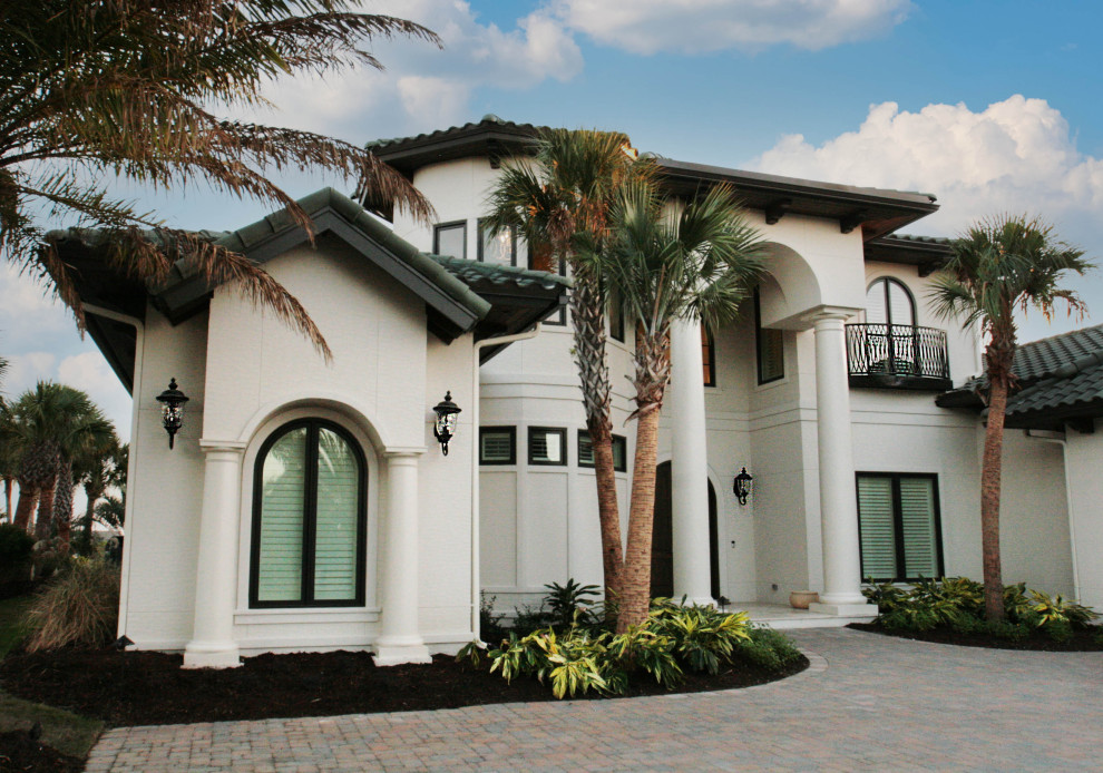 Inspiration for a large mediterranean two-storey stucco white exterior with a gambrel roof.
