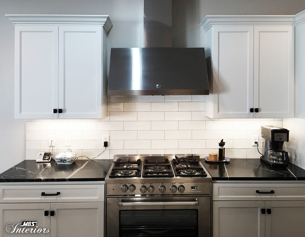 Example of a mid-sized transitional u-shaped dark wood floor and brown floor eat-in kitchen design with an undermount sink, recessed-panel cabinets, white cabinets, soapstone countertops, white backsplash, subway tile backsplash, stainless steel appliances and an island