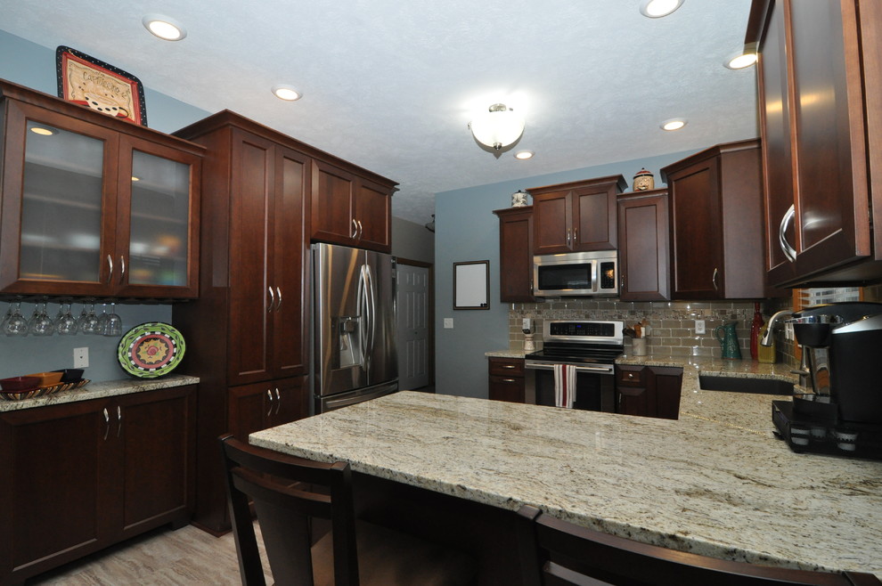 Inspiration for a mid-sized transitional u-shaped porcelain tile eat-in kitchen remodel with an undermount sink, recessed-panel cabinets, dark wood cabinets, granite countertops, beige backsplash and stainless steel appliances