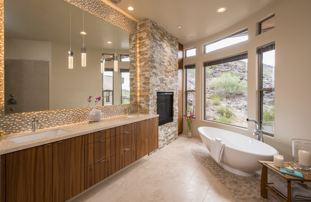 This is an example of a master bathroom in Phoenix with an undermount sink, flat-panel cabinets, dark wood cabinets, a freestanding tub, beige tile and beige walls.