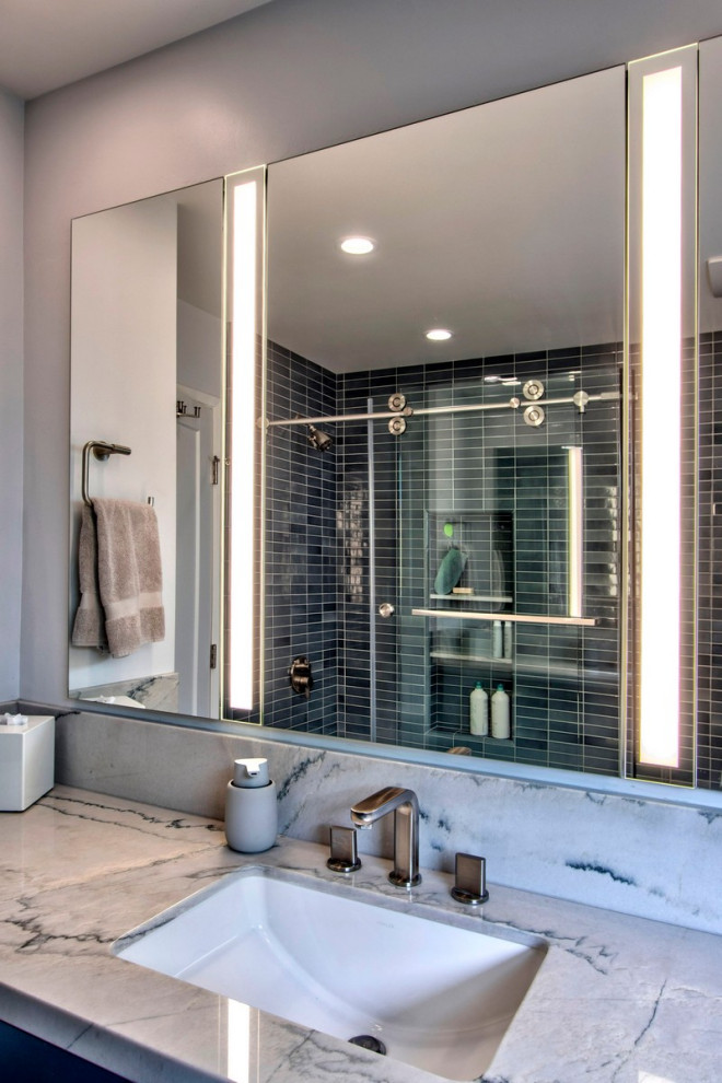 Bild på ett litet retro vit vitt badrum, med släta luckor, blå skåp, ett hörnbadkar, en hörndusch, blå kakel, terrazzogolv, ett undermonterad handfat, bänkskiva i kvartsit och dusch med skjutdörr