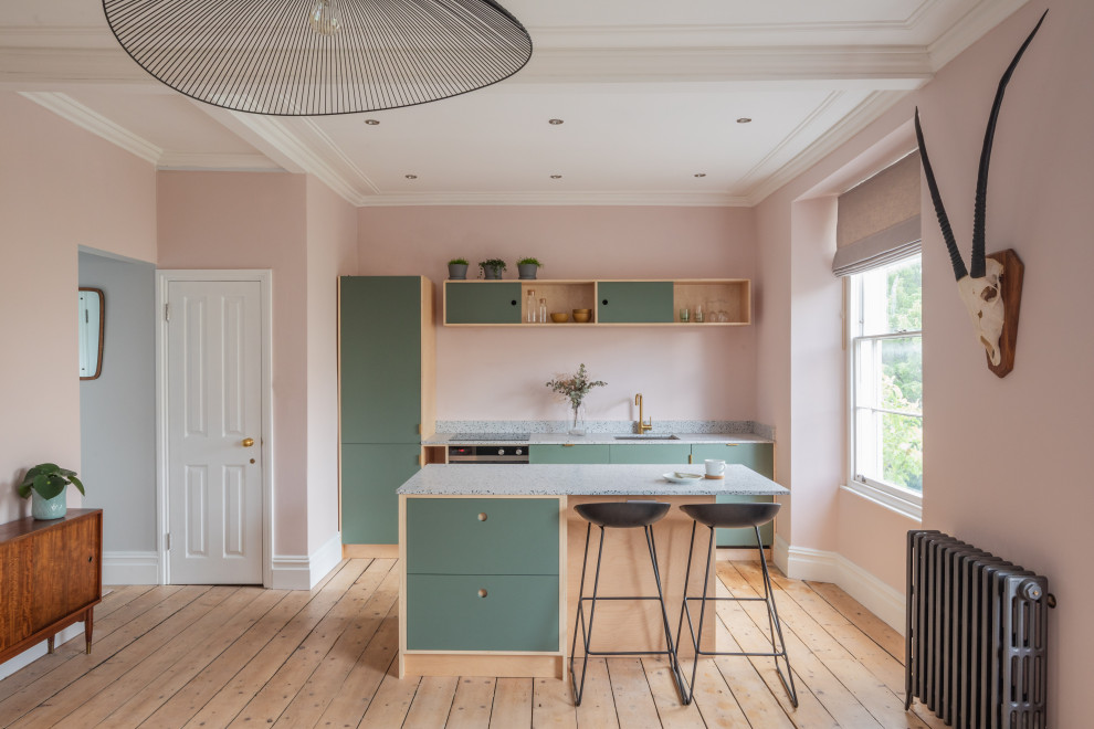 Scandi galley kitchen with a submerged sink, flat-panel cabinets, green cabinets, stainless steel appliances, light hardwood flooring, beige floors and grey worktops.