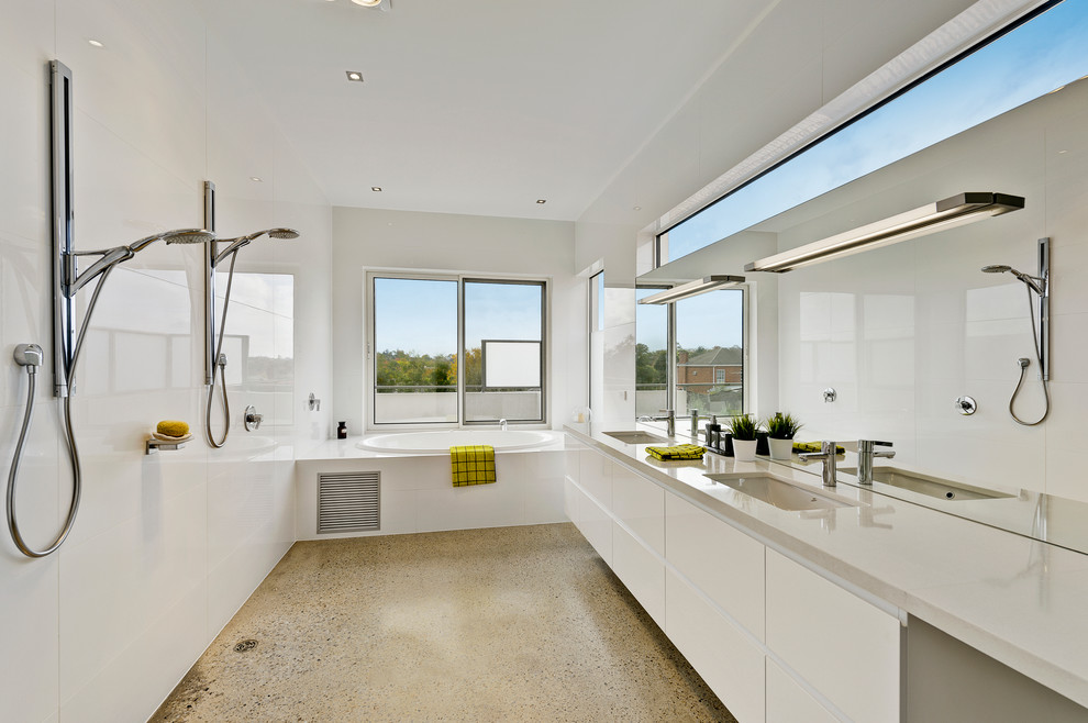 Photo of a contemporary bathroom in Melbourne with an undermount sink, flat-panel cabinets, white cabinets, a drop-in tub, an open shower, white tile, white walls and an open shower.
