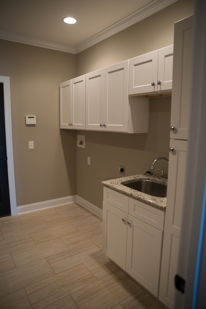 Mid-sized arts and crafts single-wall dedicated laundry room in Other with an undermount sink, shaker cabinets, white cabinets, granite benchtops, beige walls, travertine floors and a side-by-side washer and dryer.