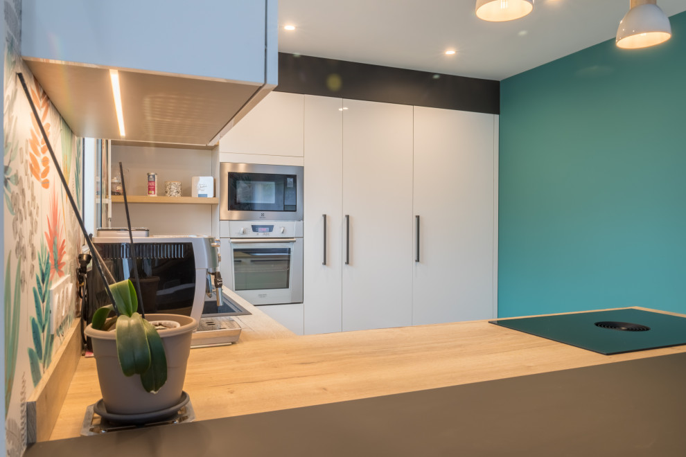 Design ideas for a medium sized modern u-shaped kitchen/diner in Other with a single-bowl sink, flat-panel cabinets, white cabinets, wood worktops, wood splashback, stainless steel appliances, a breakfast bar and a drop ceiling.