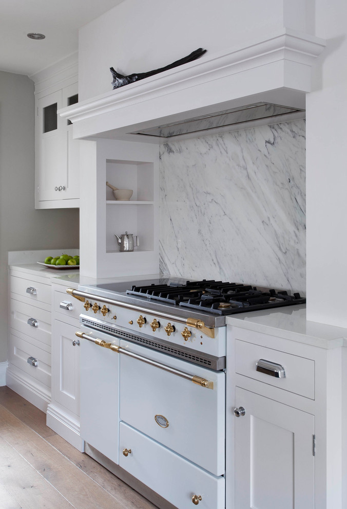 Inspiration for a large traditional u-shaped open plan kitchen in Dublin with shaker cabinets, white cabinets, marble benchtops, grey splashback, marble splashback, white appliances, medium hardwood floors, with island, brown floor and grey benchtop.