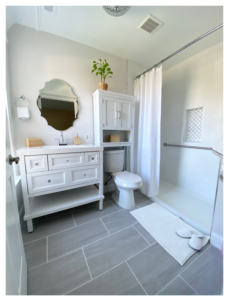 Design ideas for a mid-sized transitional bathroom in DC Metro with shaker cabinets, white cabinets, an open shower, a one-piece toilet, white tile, porcelain tile, grey walls, ceramic floors, an integrated sink, engineered quartz benchtops, grey floor, a shower curtain, white benchtops, a single vanity and a freestanding vanity.
