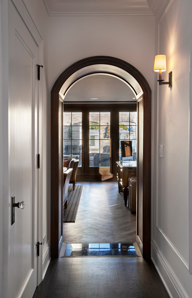 This is an example of a large traditional hallway in Chicago with white walls and dark hardwood floors.