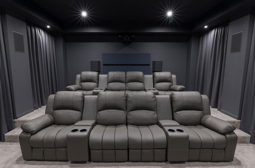 This is an example of a mid-sized modern enclosed home theatre with grey walls, carpet, a projector screen and grey floor.