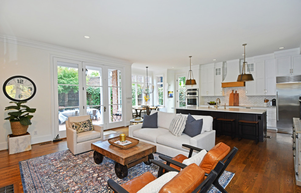Large transitional galley medium tone wood floor and brown floor open concept kitchen photo with a farmhouse sink, recessed-panel cabinets, white cabinets, quartz countertops, white backsplash, marble backsplash, stainless steel appliances, an island and white countertops