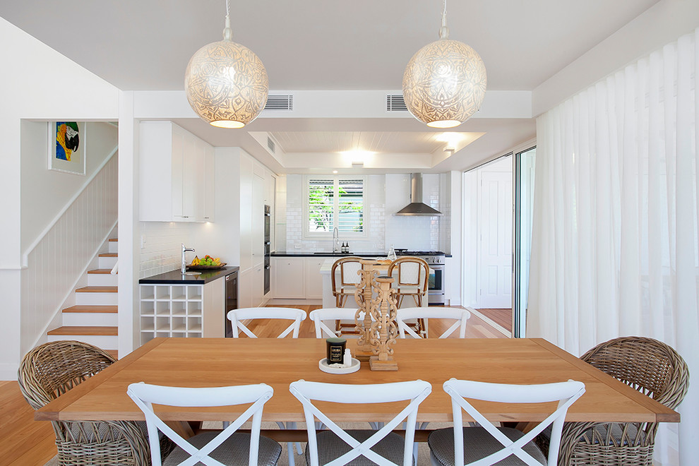 This is an example of a large eclectic open plan dining in Sunshine Coast with white walls and light hardwood floors.