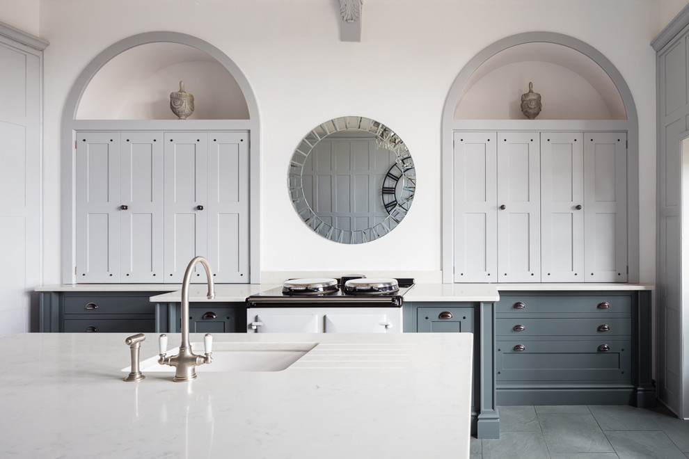 Inspiration for a traditional separate kitchen in Other with an undermount sink, shaker cabinets, solid surface benchtops, white splashback, white appliances, slate floors, with island, grey floor and white benchtop.