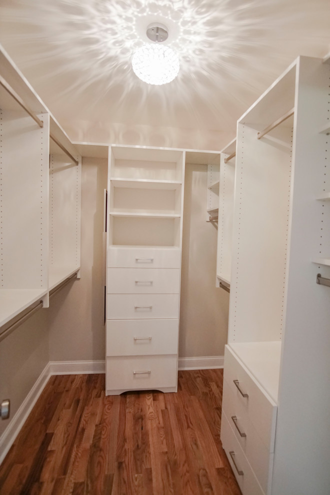 Small traditional gender-neutral walk-in wardrobe in Atlanta with flat-panel cabinets, white cabinets, light hardwood floors and brown floor.