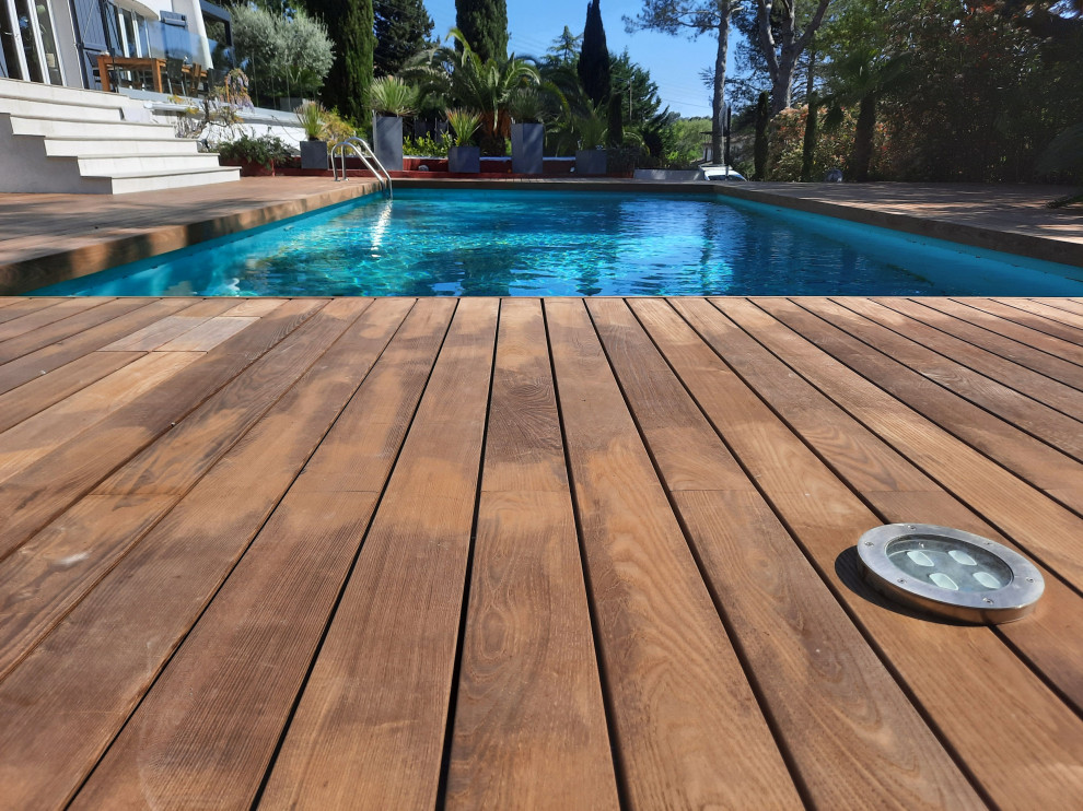 Idée de décoration pour un piscine avec aménagement paysager arrière tradition rectangle avec une terrasse en bois.