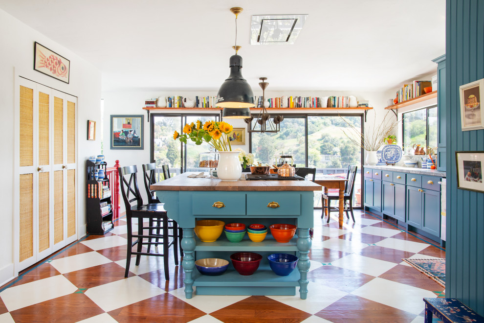 Mittelgroße Stilmix Küche in L-Form mit Schrankfronten im Shaker-Stil, blauen Schränken, Granit-Arbeitsplatte, bunter Rückwand, Küchengeräten aus Edelstahl, gebeiztem Holzboden, Kücheninsel, buntem Boden und grauer Arbeitsplatte in Los Angeles