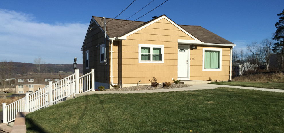 Small traditional one-storey yellow house exterior in New York with concrete fiberboard siding, a gable roof and a shingle roof.
