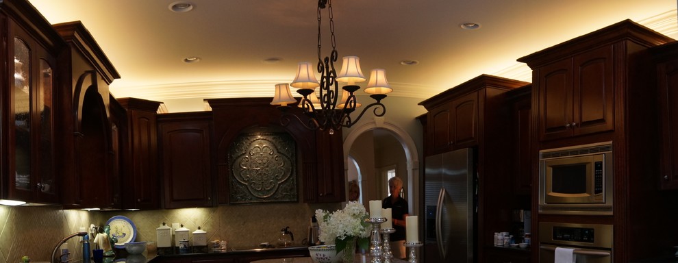 Inspiration for a large transitional u-shaped eat-in kitchen remodel with raised-panel cabinets, dark wood cabinets, granite countertops, beige backsplash, ceramic backsplash, stainless steel appliances and an island