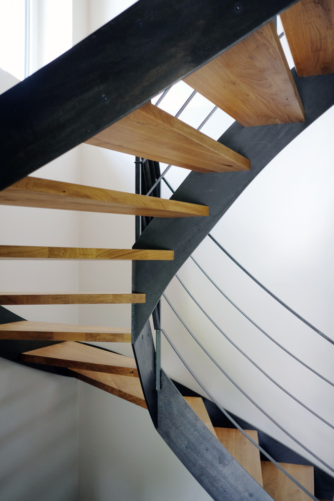 Cette photo montre un escalier courbe industriel avec des marches en bois et un garde-corps en métal.
