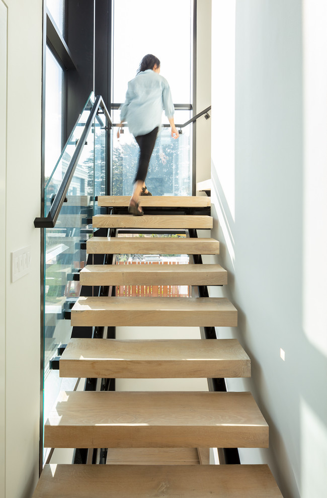 Imagen de escalera en L contemporánea grande sin contrahuella con escalones de madera y barandilla de metal