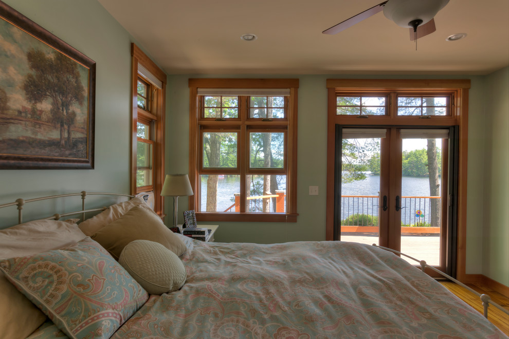 This is an example of an arts and crafts master bedroom with green walls and medium hardwood floors.