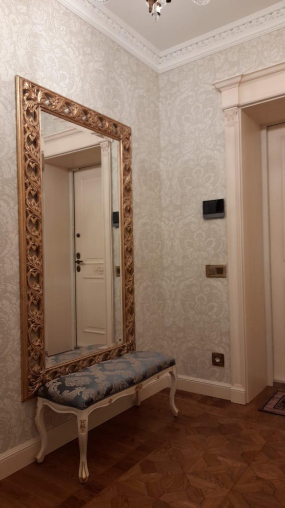 Imagen de puerta principal tradicional de tamaño medio con paredes blancas, suelo de madera oscura, puerta de madera en tonos medios, suelo marrón, bandeja y papel pintado