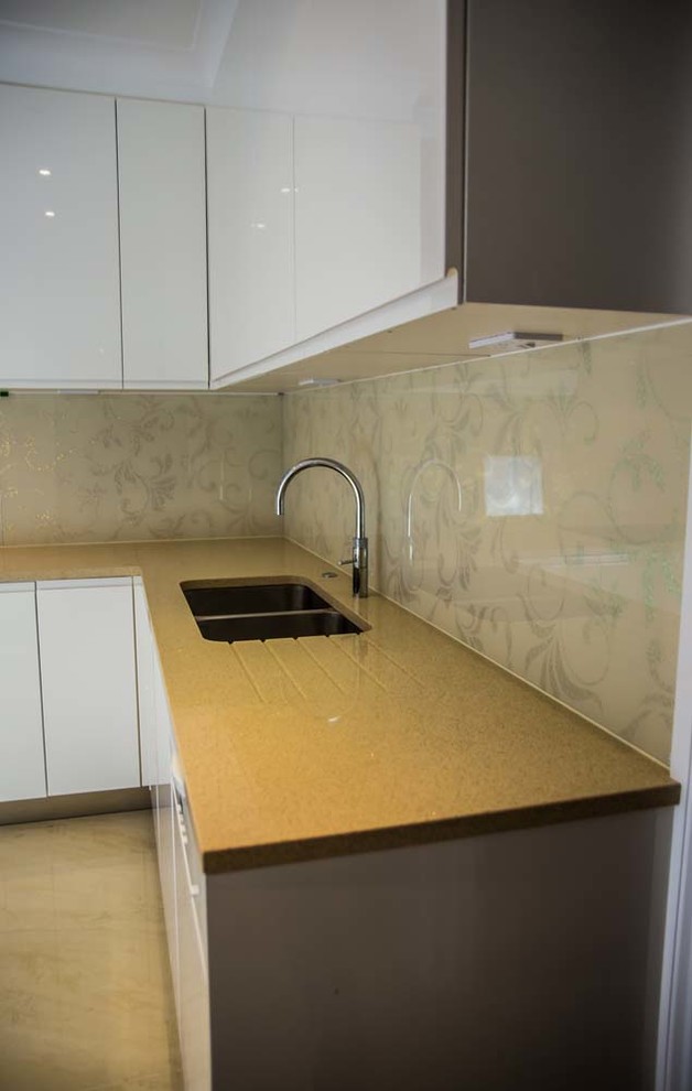 Design ideas for a large modern galley eat-in kitchen in Hertfordshire with beige splashback and glass sheet splashback.