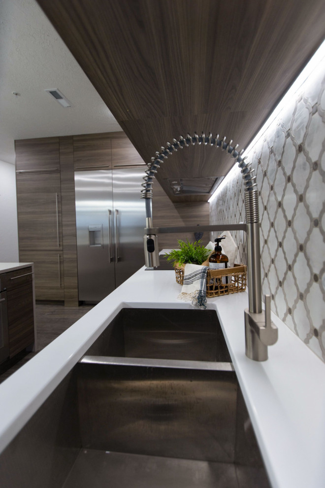 Medium sized modern l-shaped kitchen/diner in Salt Lake City with a built-in sink, flat-panel cabinets, medium wood cabinets, engineered stone countertops, multi-coloured splashback, stainless steel appliances, an island and white worktops.
