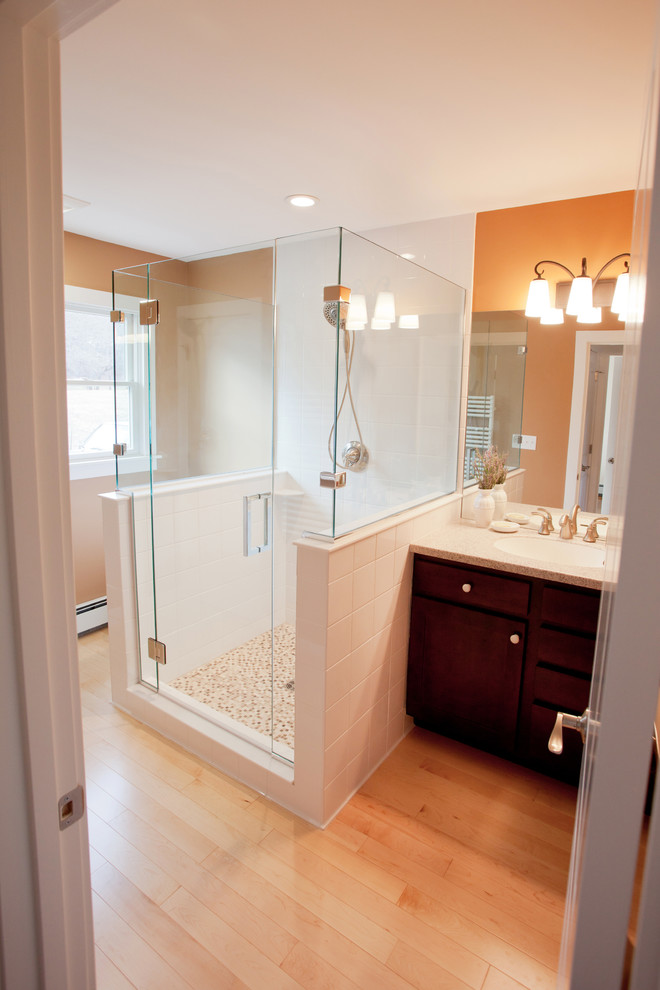 Photo of a mid-sized transitional master bathroom in Boston with dark wood cabinets, an alcove shower, white tile, porcelain tile, brown walls, light hardwood floors, an undermount sink, granite benchtops, recessed-panel cabinets, brown floor and a hinged shower door.
