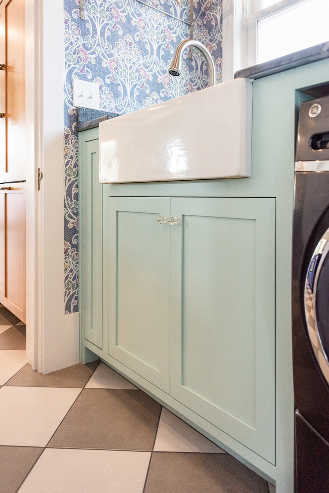 This is an example of a small eclectic galley dedicated laundry room in San Luis Obispo with a farmhouse sink, shaker cabinets, turquoise cabinets, multi-coloured walls, porcelain floors, a side-by-side washer and dryer, multi-coloured floor and grey benchtop.