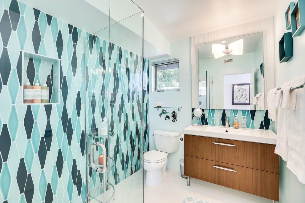 Inspiration for a large midcentury 3/4 bathroom in Los Angeles with flat-panel cabinets, light wood cabinets, a corner tub, an open shower, a one-piece toilet, white tile, stone slab, blue walls, ceramic floors, a trough sink and solid surface benchtops.