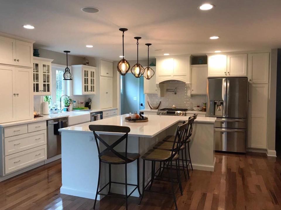 Kitchen - transitional l-shaped kitchen idea in Philadelphia with a farmhouse sink, shaker cabinets, white cabinets, marble countertops, white backsplash, subway tile backsplash, stainless steel appliances and an island