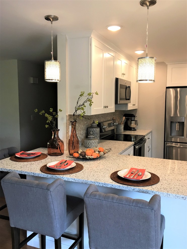 Example of a mid-sized transitional u-shaped linoleum floor and gray floor kitchen design in Seattle with an undermount sink, shaker cabinets, white cabinets, quartz countertops, gray backsplash, limestone backsplash, stainless steel appliances and a peninsula