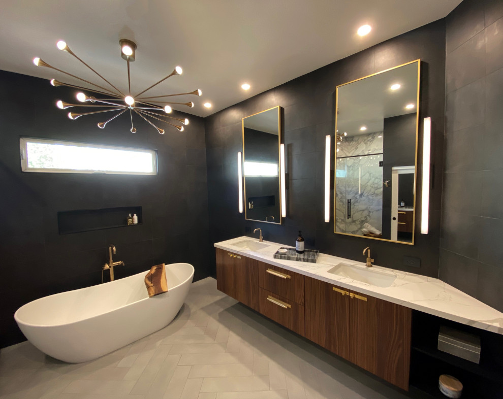 Photo of a large contemporary master bathroom in San Diego with flat-panel cabinets, medium wood cabinets, a freestanding tub, a one-piece toilet, black tile, porcelain tile, black walls, porcelain floors, an undermount sink, engineered quartz benchtops, grey floor and white benchtops.