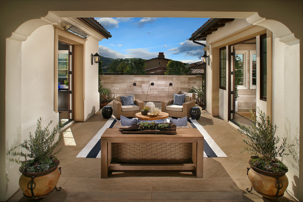 Expansive mediterranean courtyard patio in San Diego with a water feature, tile and a roof extension.