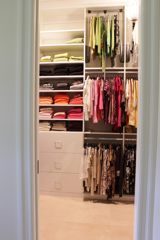 This is an example of a mid-sized contemporary women's walk-in wardrobe in New York with flat-panel cabinets, white cabinets and porcelain floors.