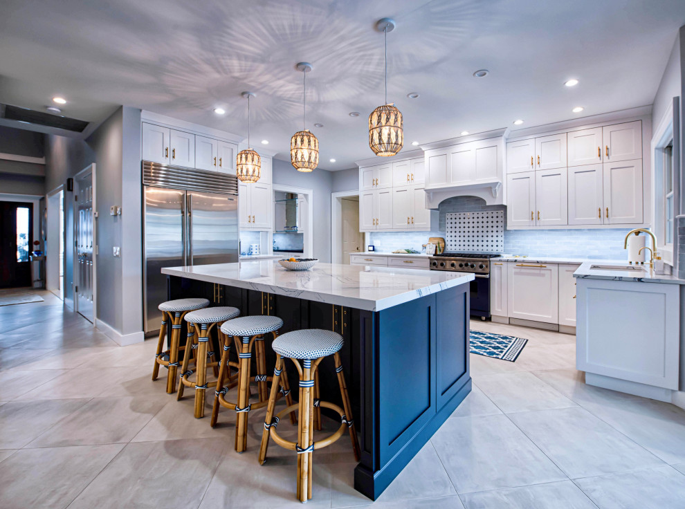 This is an example of a large beach style eat-in kitchen in New York with an undermount sink, shaker cabinets, white cabinets, quartz benchtops, blue splashback, cement tile splashback, stainless steel appliances, ceramic floors, with island, beige floor and blue benchtop.