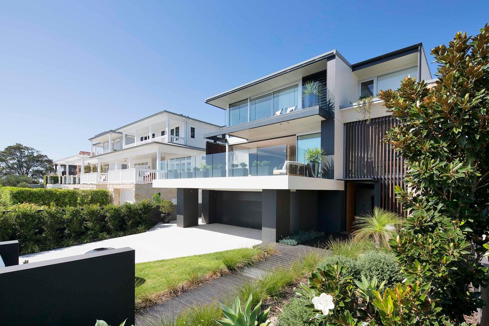 Photo of a large contemporary two-storey house exterior in Sydney with stone veneer and a flat roof.