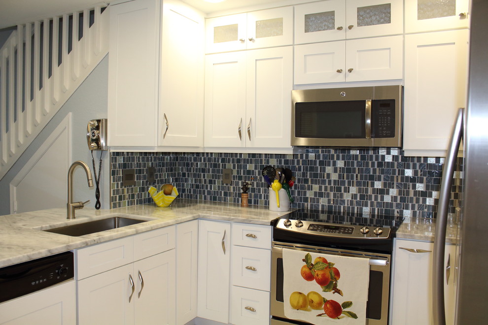 Enclosed kitchen - mid-sized transitional u-shaped porcelain tile and white floor enclosed kitchen idea in Miami with an undermount sink, shaker cabinets, white cabinets, quartzite countertops, gray backsplash, glass tile backsplash, stainless steel appliances and no island