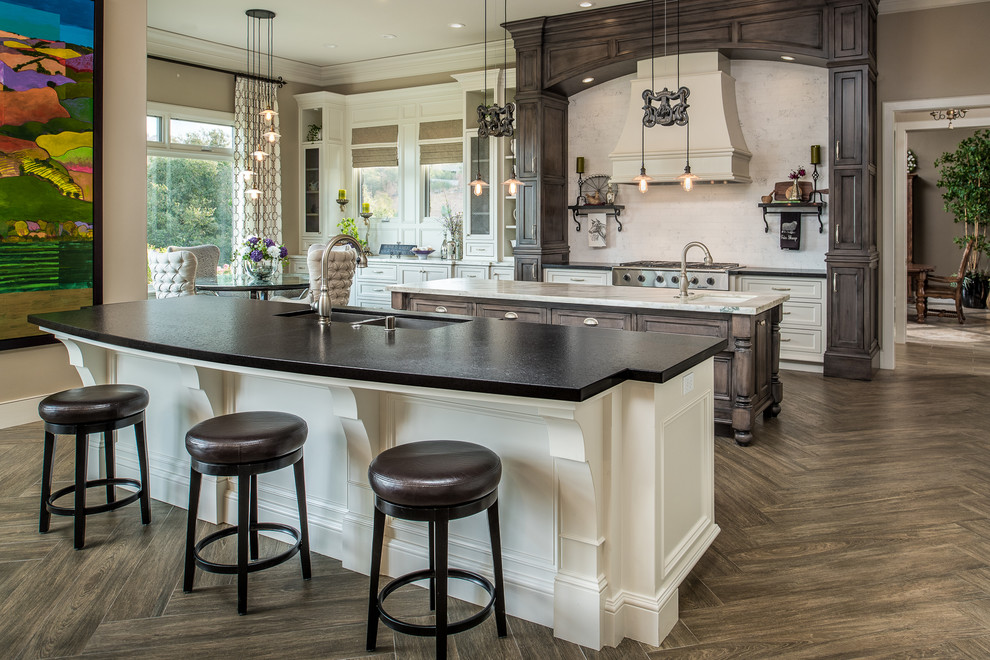 Design ideas for a traditional galley eat-in kitchen in Sacramento with an undermount sink, shaker cabinets, white cabinets, white splashback, stainless steel appliances, dark hardwood floors and multiple islands.