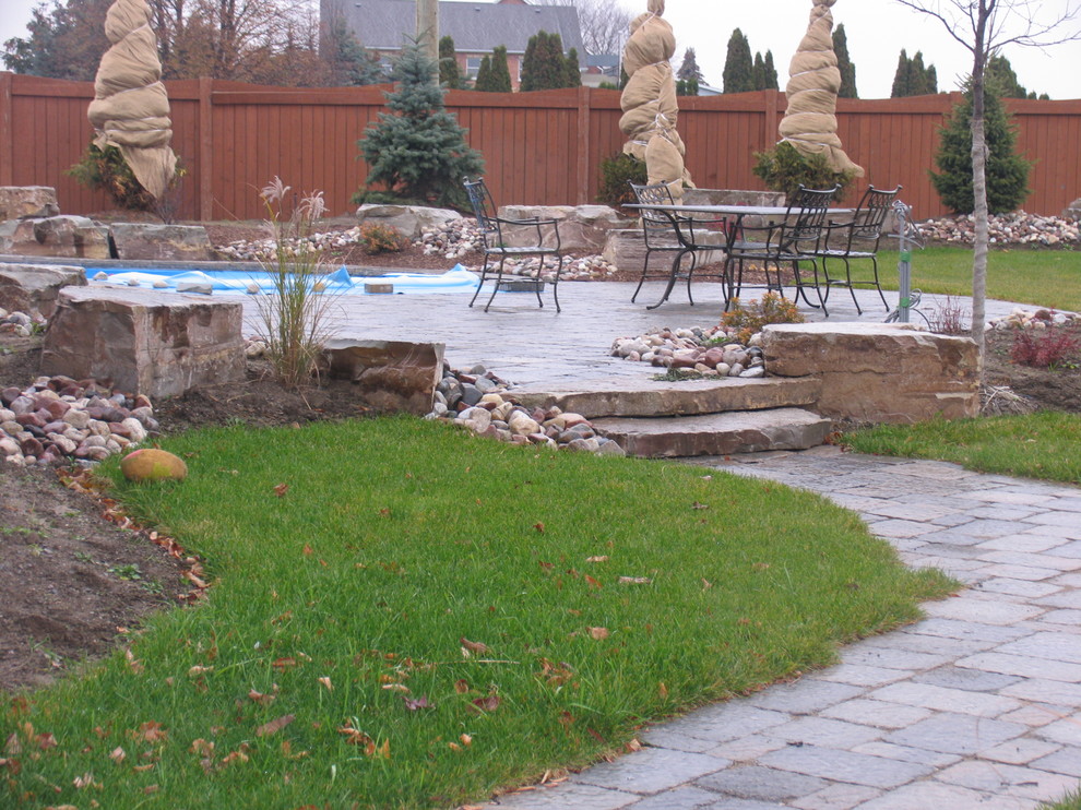 Photo of an arts and crafts front yard patio in Toronto with natural stone pavers and no cover.