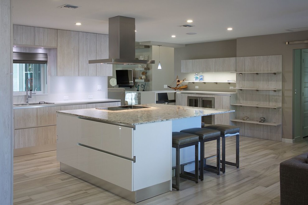 Inspiration for a mid-sized beach style eat-in kitchen in Miami with a single-bowl sink, flat-panel cabinets, light wood cabinets, quartz benchtops, stainless steel appliances, porcelain floors and with island.