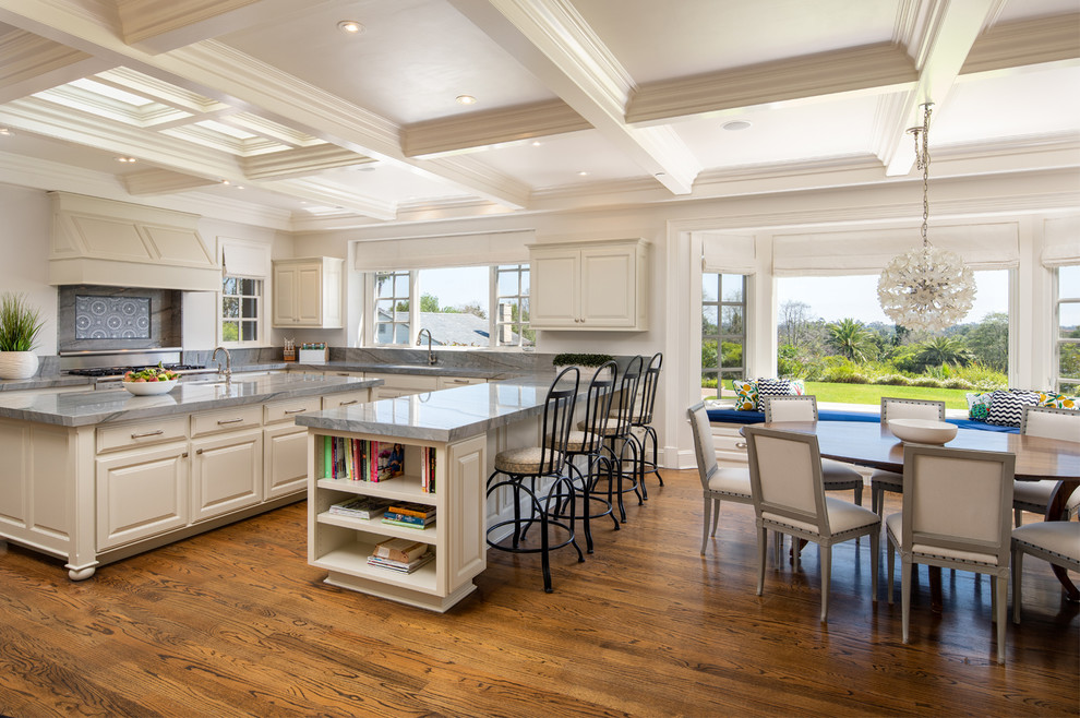 Mid-sized traditional u-shaped eat-in kitchen in San Diego with a double-bowl sink, raised-panel cabinets, white cabinets, quartzite benchtops, blue splashback, mosaic tile splashback, panelled appliances, medium hardwood floors, with island, brown floor and blue benchtop.