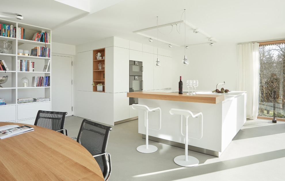 Design ideas for a mid-sized modern single-wall eat-in kitchen in Stuttgart with flat-panel cabinets, white cabinets, black appliances, vinyl floors, with island, grey floor and white benchtop.