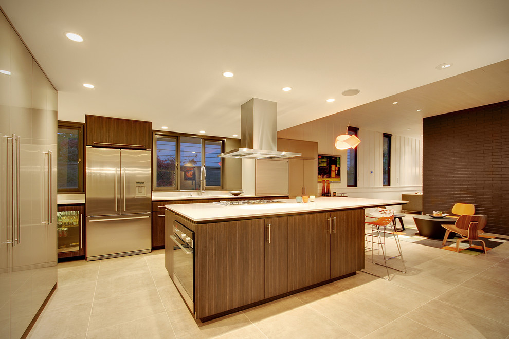 Photo of a large midcentury galley open plan kitchen in Seattle with an undermount sink, flat-panel cabinets, dark wood cabinets, solid surface benchtops, stainless steel appliances, cement tiles, with island and grey floor.